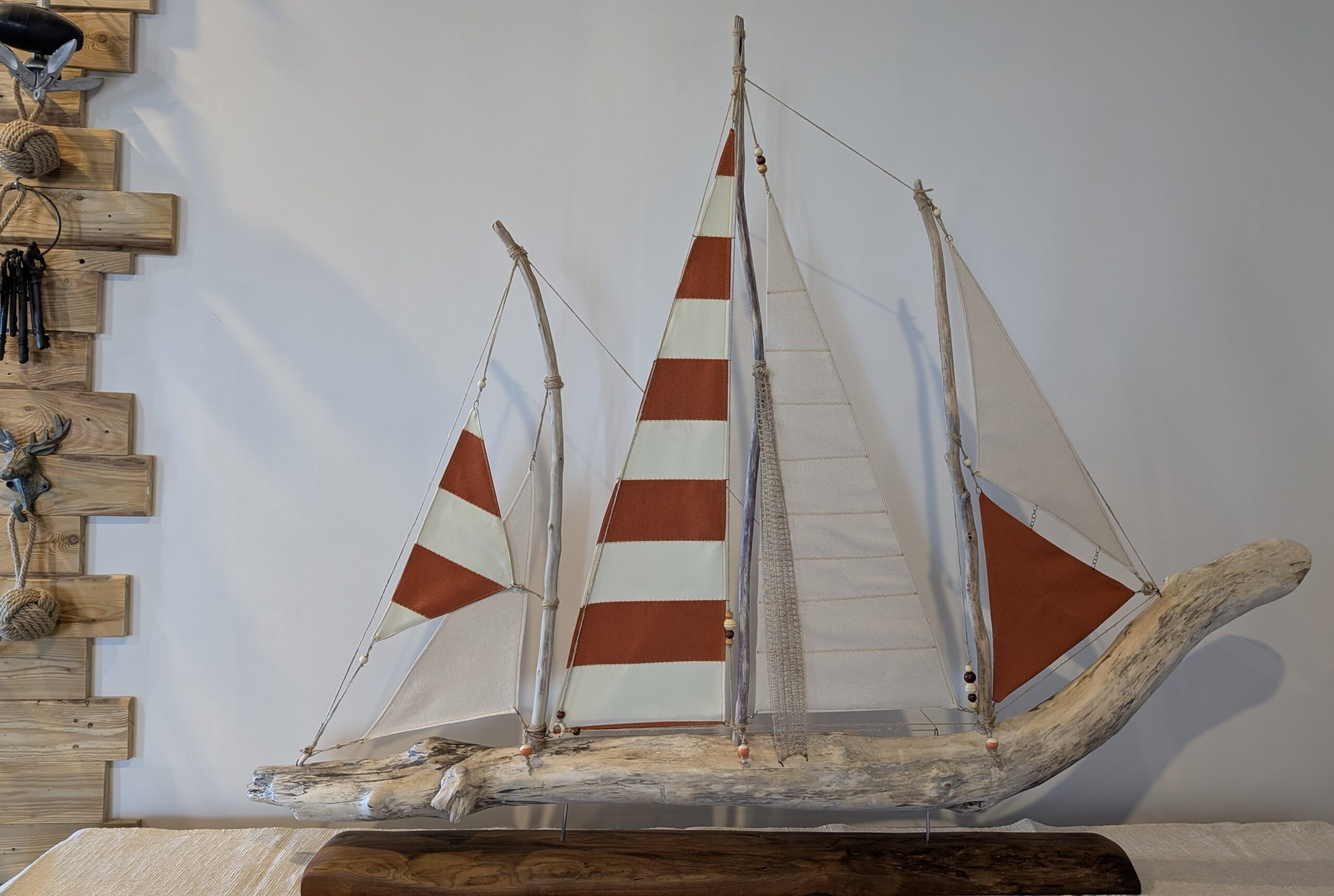 Le coureur des vents, voilier à trois mâts et aux voiles orange et ivoire sur une coque en bois flotté